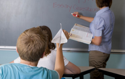 Barn med ADHD kastar ett pappersflygplan i klassrummet.