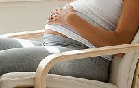 Pregnant woman sitting on chair with baby scan photos