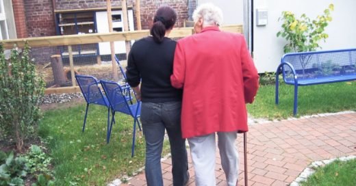 Vårdbiträde går på promenad med patient med demenssjukdom. 
