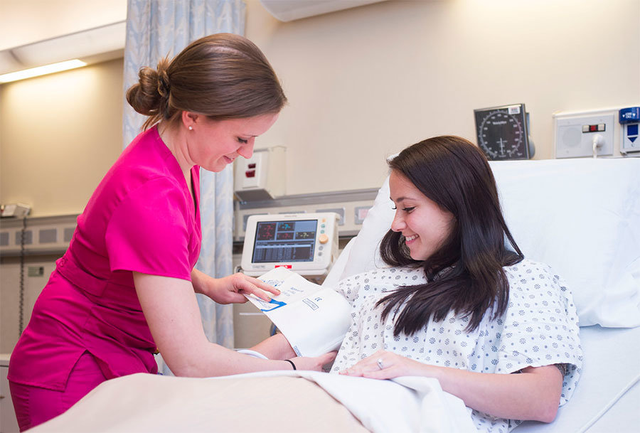 En sköterska mäter en ung kvinnas blodtryck på sjukhuset.