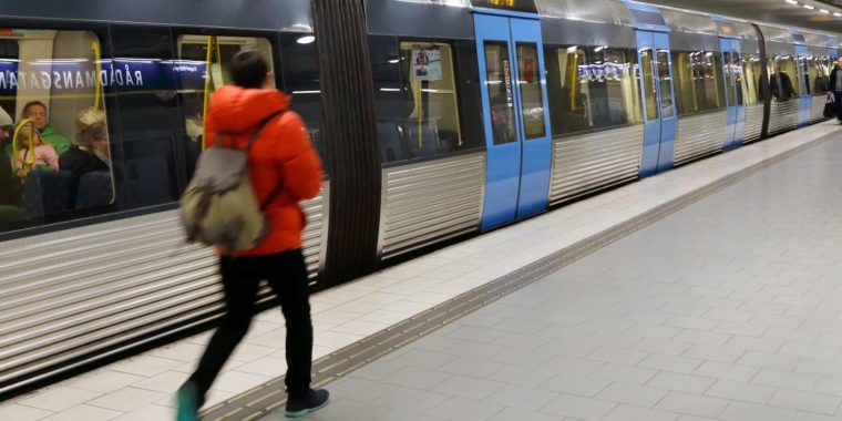 Tunnelbanetåg med stängda dörrar och passagerar på plattformen, vid station Rådmansgatan i Stockholm, Sverige.