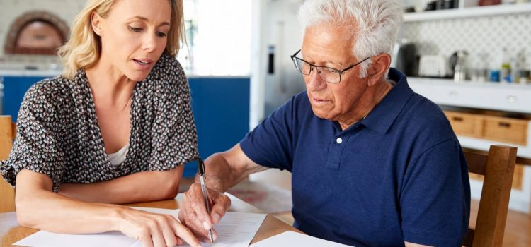 Kvinna hjälper äldre man att fylla i dokument