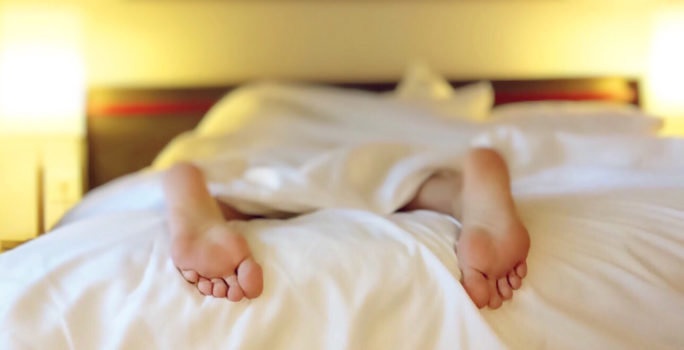 Kvinna som ligger i sängen och sover på grund av järnbrist, ett vanligt symptom som drabbar många.