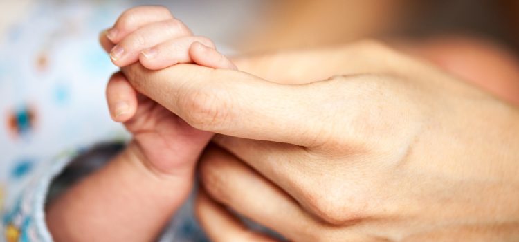 Nyfött barn håller sin mammas pekfinger